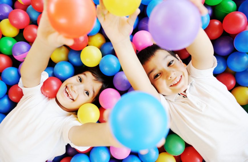 Two kids happily playing at a ball pit