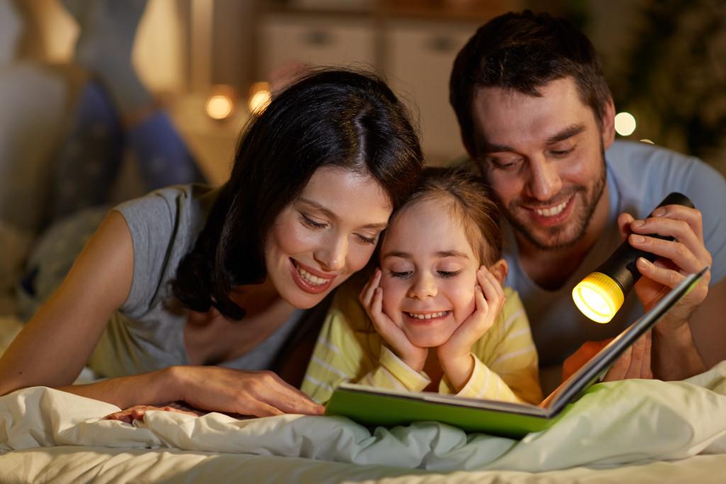 mom and dad with daughter in bed reading a book